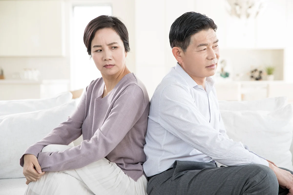 정신적 피해 위자료 액수 기준|서로 등을 돌리고 앉아 갈등을 겪는 중년 부부의 모습