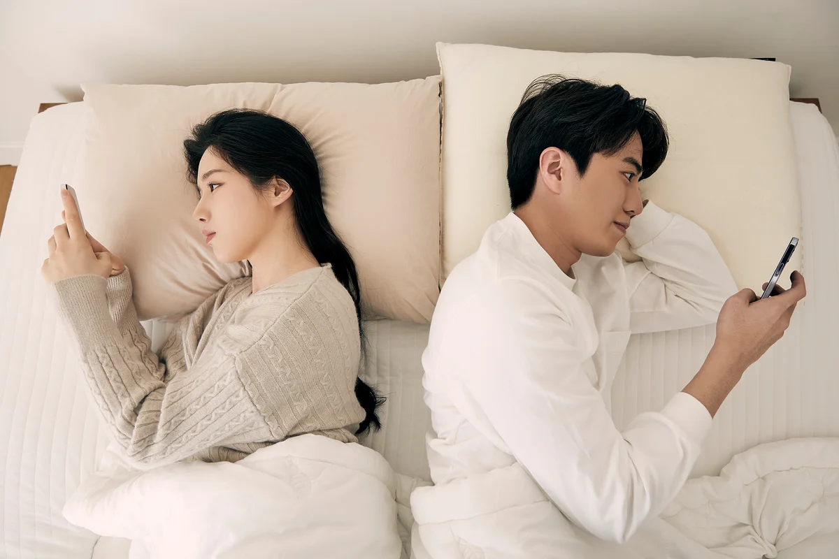 서초 특유재산 재산분할|침대에 누워 각자 스마트폰을 보며 소통이 단절된 커플